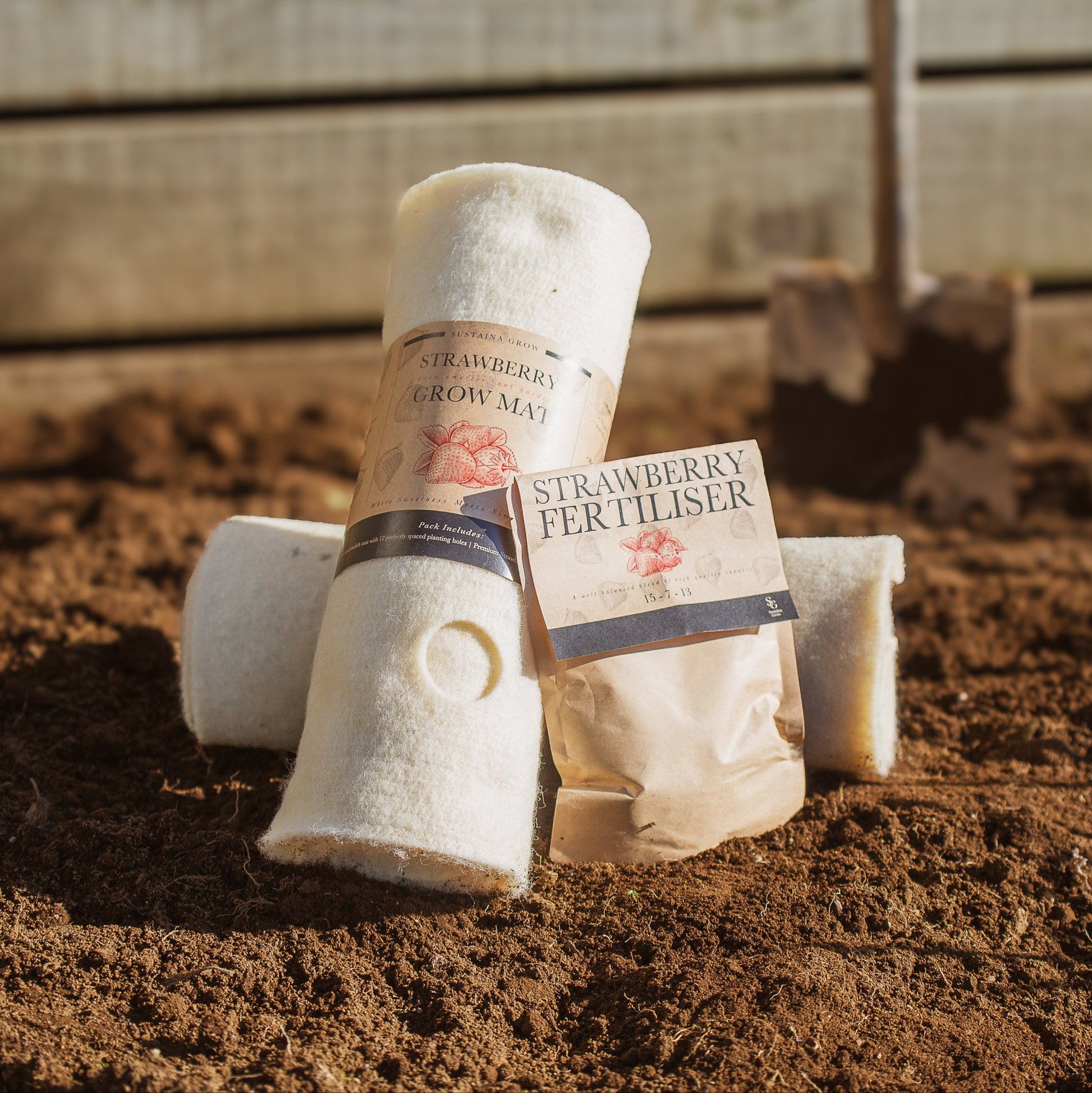 Strawberry fertilizer bags and wool grow mats on a soil surface with wooden background